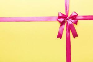 Top view of purple ribbon rolled and pink bow isolated on colored background. Flat lay with copy space photo