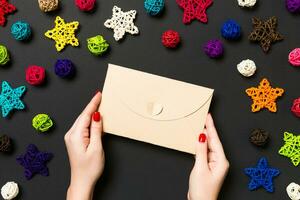 Top view of woman holding an envelope on black background made of holiday decorations. Christmas time concept photo