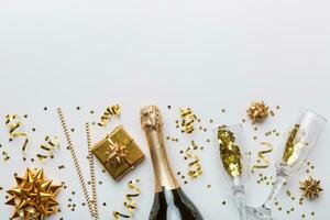 Bottle of champagne with colored glitter, confetti and gift box space for text on colorfull background, top view. Hilarious, christmas and birthday celebration photo