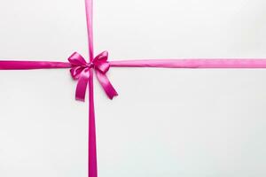 Top view of purple ribbon rolled and pink bow isolated on colored background. Flat lay with copy space photo