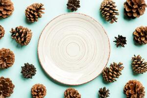 Top view of festive plate with pine cones on colorful background. New Year dinner concept photo