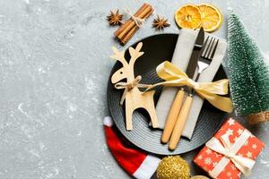 Top view of holiday dinner decorated with dried fruit and cinnamon on cement background. Set of plate, urensil and New Year decorations. Christmas time concept with epmty space for your design photo