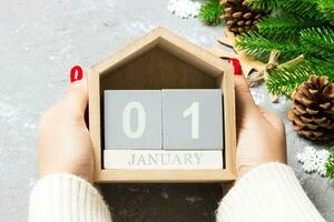 Top view of female hands holding a calendar on cement background. The first of January. Holiday decorations. New Year concept photo