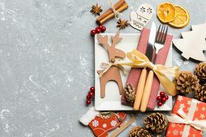 Top view of holiday dinner decorated with dried fruit and cinnamon on cement background. Set of plate, urensil and New Year decorations. Christmas time concept with epmty space for your design photo