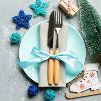 Holiday composition of Christmas dinner on cement background. Top view of plate, utensil and festive decorations. New Year Advent concept with copy space photo