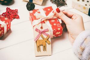 Top view of female hand tie up New Year present on festive wooden background. Christmas time concept photo