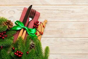 vista superior de tenedor y cuchillo en servilleta con adornos navideños y árbol de año nuevo sobre fondo de madera. vacaciones y concepto festivo con espacio de copia foto