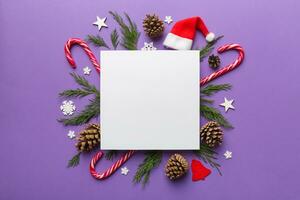 Flat lay Christmas composition. square Paper blank, pine tree branches, christmas decorations on Colored background. Top view, copy space for text photo