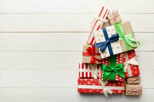 Christmas tree made of beautifuly wrapped presents on colored background, view from above. New Year gift box minimal concept with copy space photo