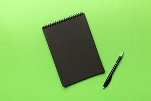 school notebook on a colored background, spiral black notepad on a table Top view photo