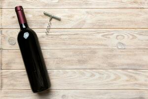 One Bottle of red wine with corkscrew on colored table. Flat lay, top view wth copy space photo