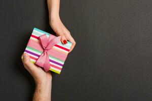 Top view of a man and a woman holding a gift box on colorful background. Love and relationship concept. Copy space photo