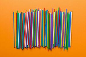 many multi-colored plastic tubes for cocktail on Colored background, top view photo