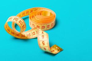 Close up of tangled measuring tape on blue background. Fitness and healthy diet concep with perspective view photo