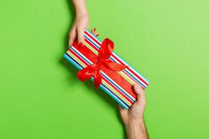 Top view of a man and a woman holding a gift on colorful background. Concept of giving and receiving a present. Close up photo