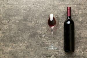 Glass of red wine and a bottle on colored table. Flat lay, top view wth copy space photo