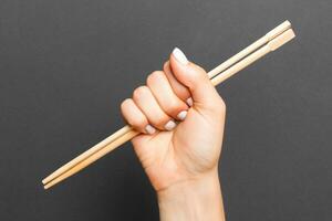 Woman's hand holding chopsticks on black background. Chinese food concept with empty space for your design photo