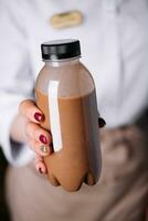 woman holding chocolate smoothies in plastic bottles photo