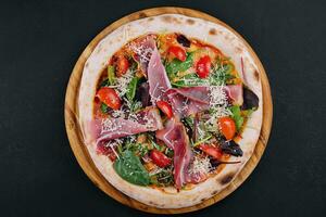 Pizza with prosciutto meat on wooden board photo