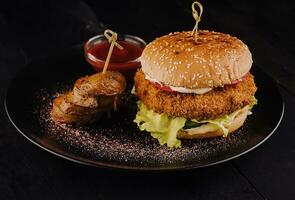 Delicious crusty fish burger and potatoes slices photo