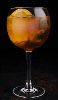 transparent glass with a bright orange alcoholic drink and ice cubes photo