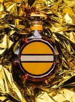 bottle of cognac on golden foil background photo