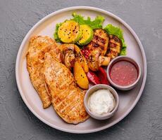 grilled chicken breast with vegetables and sauces photo
