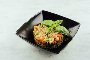 couscous tartare with vegetables in black plate photo