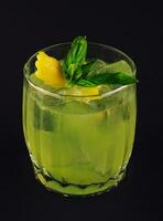 Fresh summer green basil cocktail in a glass on dark background photo