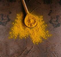 Yellow curry spice with wooden spoon photo