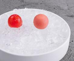 cherry tomatoes lie on ice in a white bowl photo