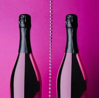 two champagne bottles on pink background photo