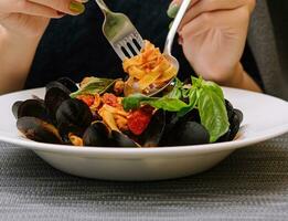 mujer comiendo pasta con mejillones en un restaurante foto