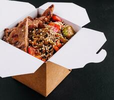 de cerca de tallarines en un caja con vegetales y carne de vaca en teriyaki salsa foto