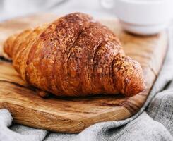 croissant with chocolate powder on a wooden board photo