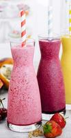 Three different smoothies of berry, banana with tangerine, kiwi, strawberries photo