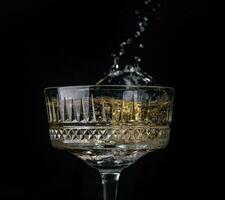 Glass of champagne with splash, isolated on black background photo