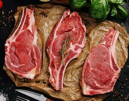 Three raw beef steaks on a wooden chopping board photo