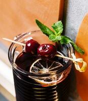 Glass of alcohol tincture made from cherry fruits photo