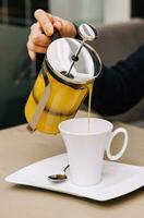 A woman pours sea buckthorn tea from a teapot into a mug photo
