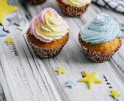 Delicious cupcakes with colorful cream on wood table photo
