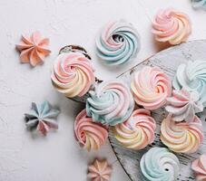 Multicolored meringue on wooden tray top view photo