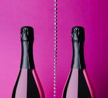 two champagne bottles on pink background photo