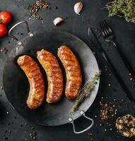 fried sausages on black pan from above photo