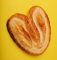 Butterfly puff pastry or palmier cookie on yellow background photo