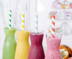 Four different smoothies of berry, banana with tangerine, kiwi, strawberries photo