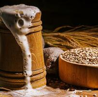 Wooden beer mug with beer and foam standing on a wooden table photo