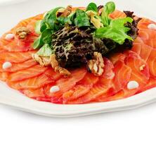 Salmon carpaccio with salad on plate photo