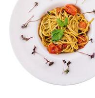 Spaghetti with colorful stewed cherry tomatoes, basil and pesto sauce photo