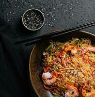 Stir fry noodles with vegetables and shrimps in black bowl photo